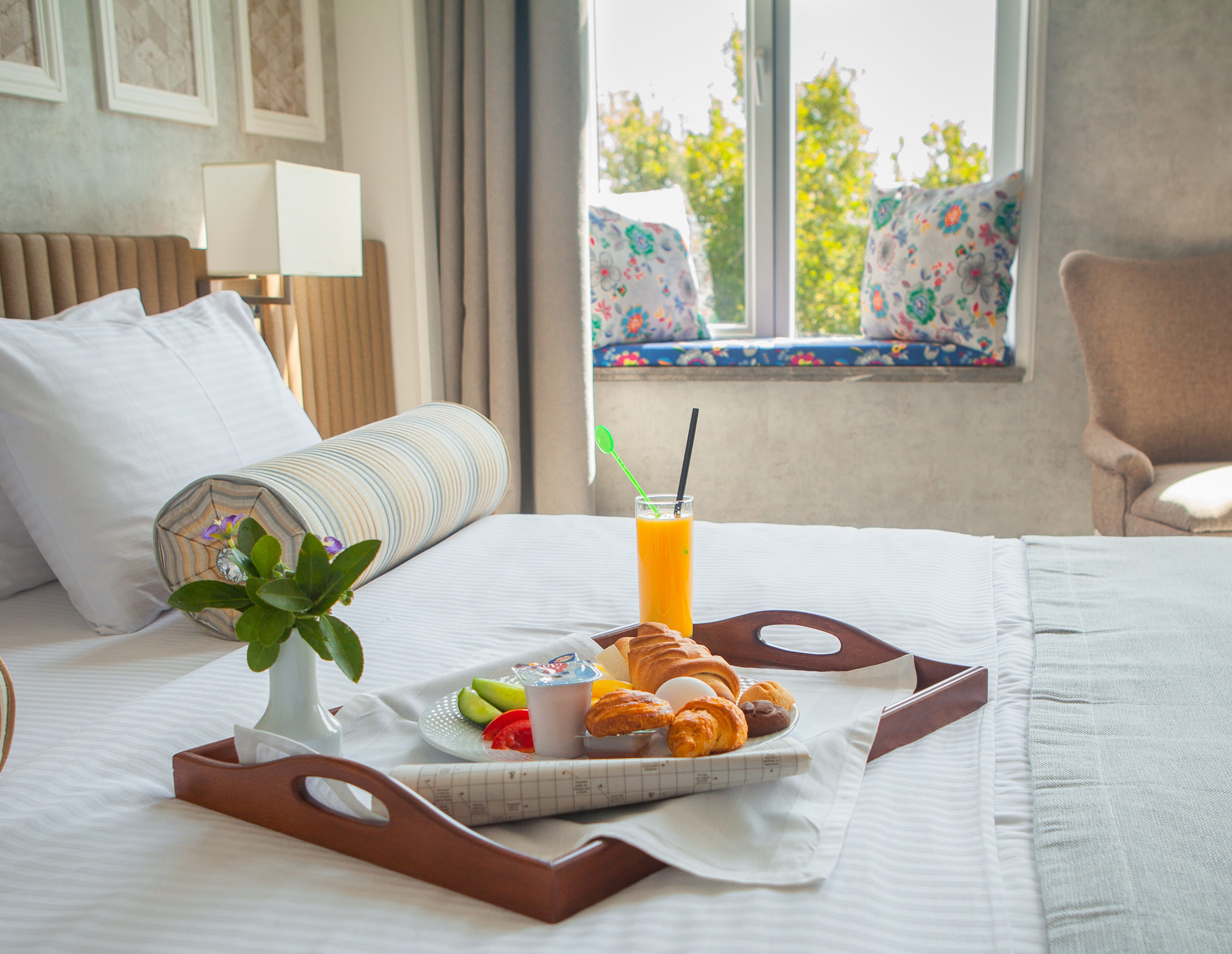 croissant, boiled egg, orange juice, yogurt breakfast on tray in bed in hotel room 1