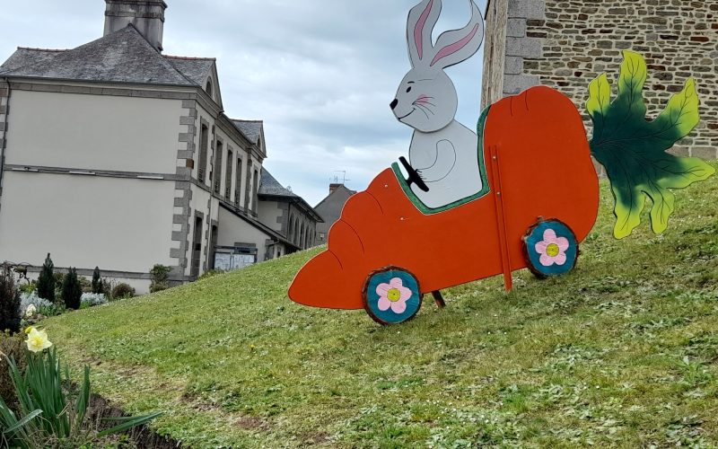 décor de pâques avec un lapin blanc dans une voiture orange en forme de carotte