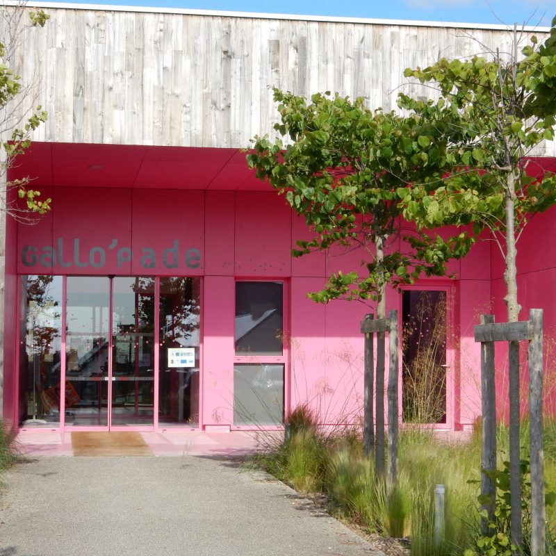 maison de l'enfance gallo'pade bâtiment rose et en bois naturel avec des arbres à l'entrée